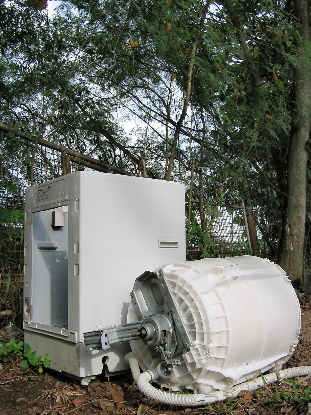 Discarded washing machine and separated drum awaiting disposal